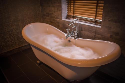 a bath tub filled with foam in a bathroom at The George Wright Boutique Hotel, Bar & Restaurant in Rotherham
