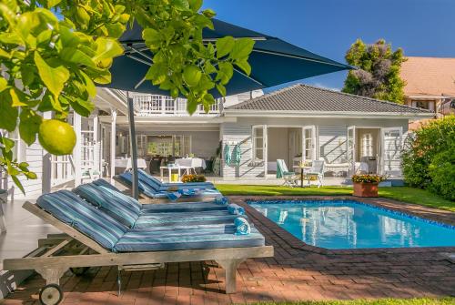 a house with a swimming pool and a blue umbrella at The Knysna Belle Guest House in Knysna