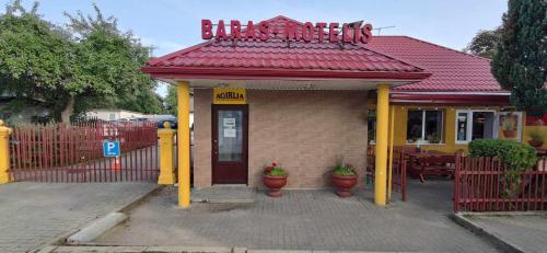 a building with a red roof and yellow columns at AGIRIJA in Panemunė