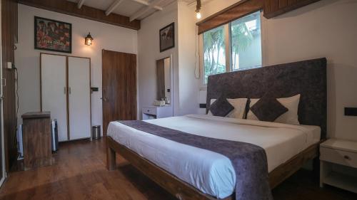 a bedroom with a large bed with a large window at Anjoned Hostel & Cafe in Anjuna