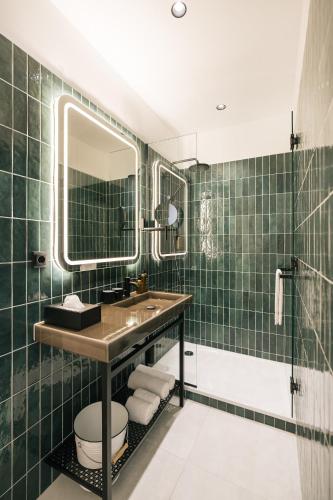 a green tiled bathroom with a sink and a mirror at Bio-Hotel Schani Wienblick in Vienna