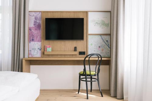 a chair sitting in front of a tv in a bedroom at Bio-Hotel Schani Wienblick in Vienna