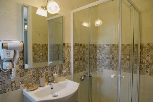 ein Bad mit einer Dusche und einem Waschbecken in der Unterkunft Rooms in Yard in Kórinthos
