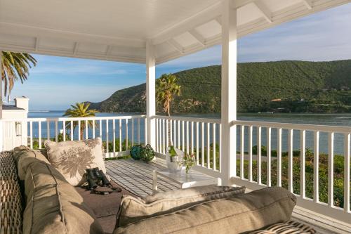 a couch on a porch with a view of the ocean at The Knysna Belle Guest House in Knysna