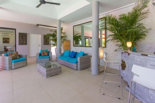 a living room with blue couches and a table at Villa Tropical Cocoon in Koh Samui 