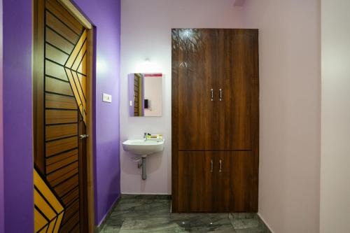 a bathroom with a sink and a wooden door at Selva Inn in Pondicherry