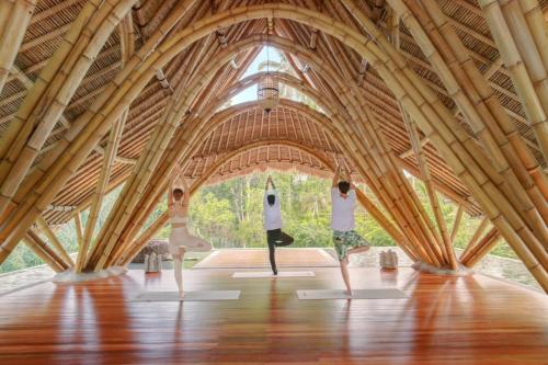 a group of three people doing yoga in a building at Aksari Resort Ubud by Ini Vie Hospitality in Tegalalang