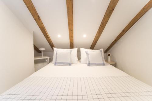 - un lit blanc dans un dortoir doté de poutres en bois dans l'établissement Fisherman's house La Pineta, à Murter