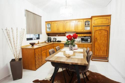 una cocina con armarios de madera y una mesa con rosas rojas. en Sweet Dreams Trikala, en Tríkala