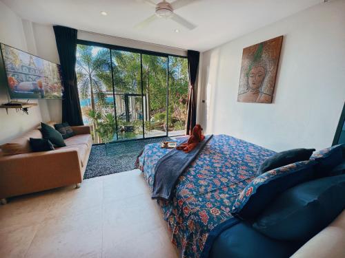 a bedroom with a bed and a couch and a window at VILLA TSAY - Nature, Privacy, Elegance in Haad Yao