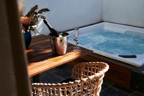 a hot tub with a bottle of wine and two chairs at Vergenoegd Löw Boutique Hotel & Spa in Cape Town
