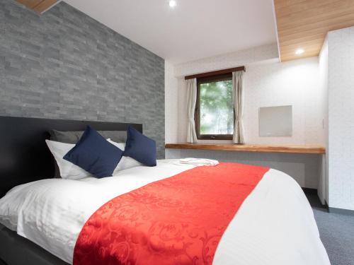 a bedroom with a red and white bed with a window at Tabist Sasebo Palace Hotel in Sasebo