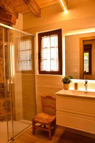 a bathroom with a shower and a sink and a chair at El Molino de Nocedo in León