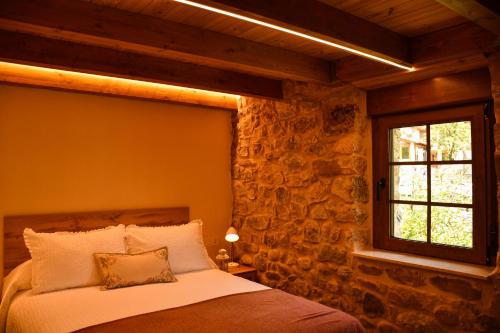 a bedroom with a bed with a stone wall at El Molino de Nocedo in León