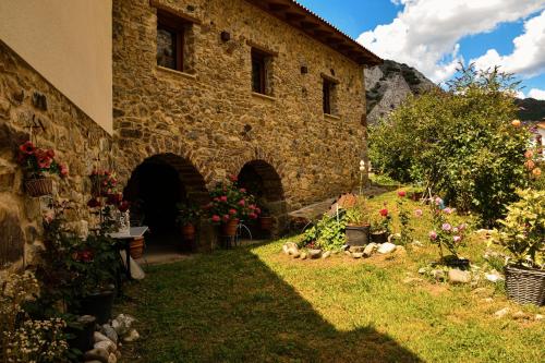 a stone building with a bunch of flowers in the yard at El Molino de Nocedo in León