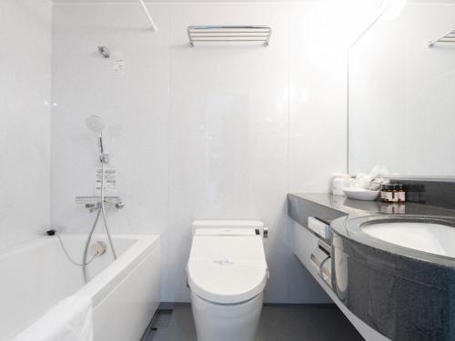 a white bathroom with a toilet and a sink at Tabist Sasebo Palace Hotel in Sasebo