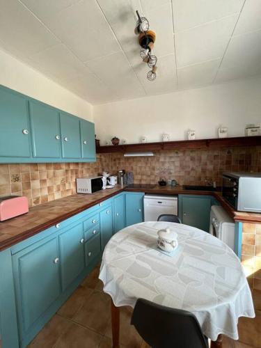 a kitchen with blue cabinets and a table in it at Gîte de Pagalot au cœur du vignoble in Virazeil