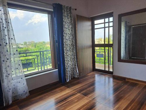a living room with a large window and a balcony at Private room in Retreat by Walias Farm Stay in Sohna