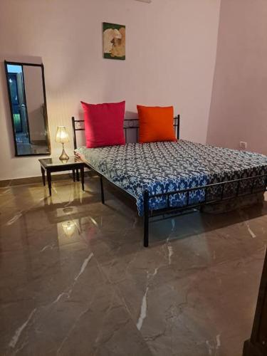 a bed with two red pillows in a room at Private room in Retreat by Walias Farm Stay in Sohna