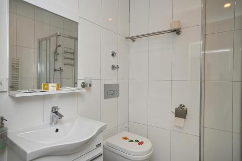 a white bathroom with a toilet and a sink at Ferienwohnung&Aparts By kispet group hotels in Oberhausen in Oberhausen