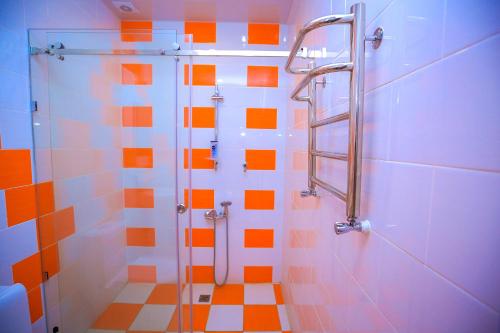 La salle de bains est pourvue d'une douche avec du carrelage blanc et orange. dans l'établissement ART SAMARQAND HOTEL, à Samarcande