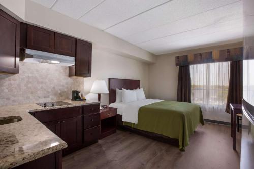 um quarto de hotel com uma cama com um cobertor verde em Quality Inn Near Princeton em Lawrence