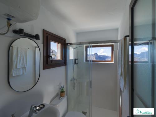 a bathroom with a shower and a sink and a mirror at Living Artenara - CAVE HOUSE & SILENCE Adults Only in Artenara