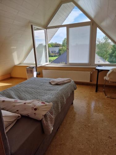 ein Schlafzimmer mit einem Bett in einem Zimmer mit großen Fenstern in der Unterkunft Haus der Erholung App OG in Lotte