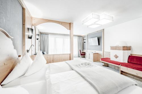 a bedroom with a large white bed and a red couch at SKI - GOLF - WELLNESS Hotel Riml in Hochgurgl