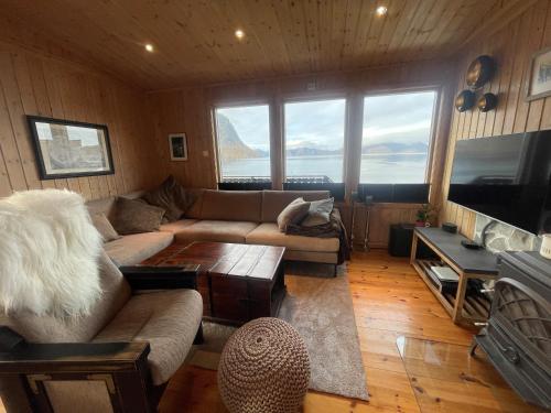 a living room with a couch and a tv and a table at Nordmannsneset på Seiland in Hammerfest