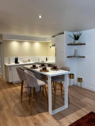 - une cuisine avec une table et des chaises blanches dans l'établissement Appartement Le O'mehr, à Saint-Omer