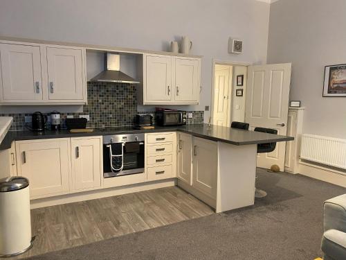 a kitchen with white cabinets and a black counter top at MMR Flats in Carlisle