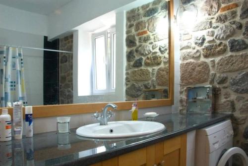 a bathroom with a sink and a stone wall at Petrini Krini Luxury Appartments in Ypsilométopon