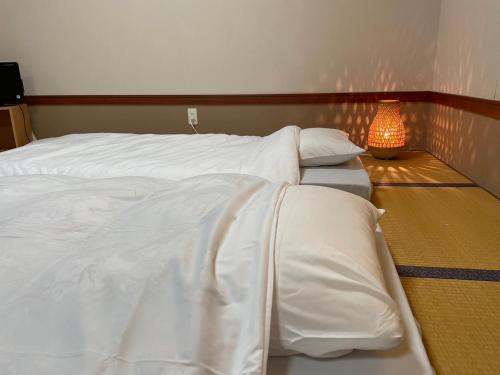 a bedroom with two beds with white sheets and a lamp at Kobohudonoyu in Sukagawa