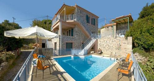 a house with a swimming pool with chairs and an umbrella at Petrini Krini Luxury Appartments in Ypsilométopon