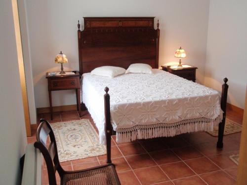 een slaapkamer met een bed en 2 tafels en een stoel bij Casa da Boa Fonte in Ponte de Lima