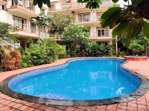 a swimming pool in front of a building at Ivy Retreat- Serviced Apartments in Baga