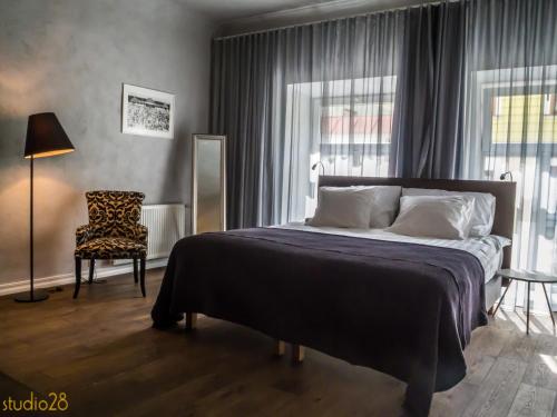 a bedroom with a large bed and a chair at Studio28 Boutique Rooms in Pärnu