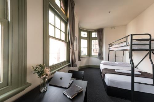a room with two beds and a laptop on a desk at Sydney Central Inn in Sydney
