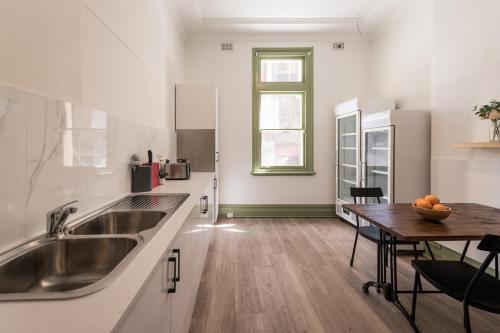 uma cozinha com um lavatório e uma mesa de madeira em Sydney Central Inn em Sydney