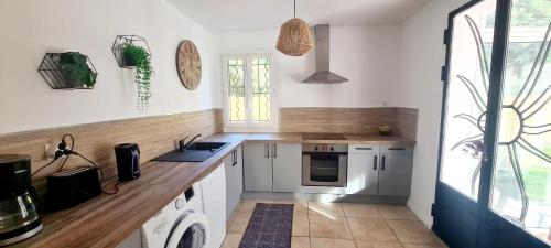 a kitchen with white cabinets and a wooden counter top at L'Ecrin des Alpilles in Graveson