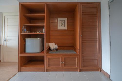 a wooden cabinet with a microwave in a room at Eco Hotel by Thammasat in Bang Lamung