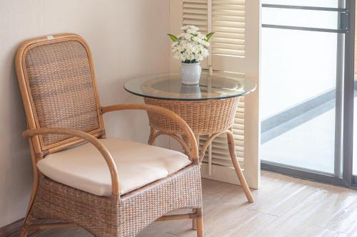 a glass table with a chair and a glass table with flowers at Eco Hotel by Thammasat in Bang Lamung