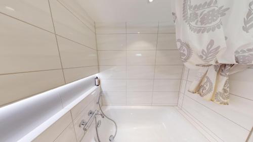 a white bathroom with a tub and a shower curtain at Über den Dächer von Chur (Calanda) in Chur