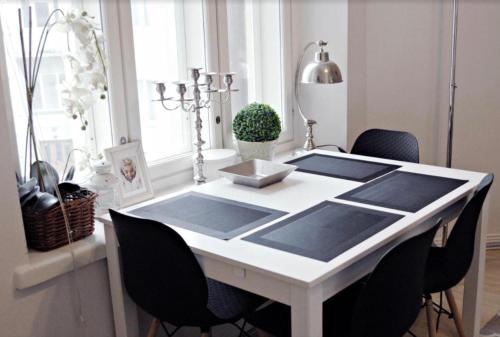 een witte eettafel met zwarte stoelen en een raam bij Scandinavian Home 21 in Heard City in Helsinki