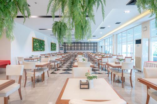 un restaurante con mesas, sillas y plantas en Eco Hotel by Thammasat en Bang Lamung