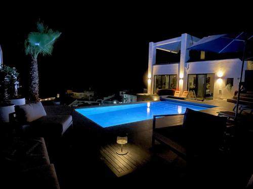 una piscina por la noche con sillas y una palmera en Villa Colina del Mar - Luxurious view near the beach, en Nerja