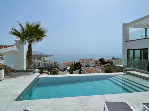 una piscina al lado de una casa en Villa Colina del Mar - Luxurious view near the beach, en Nerja