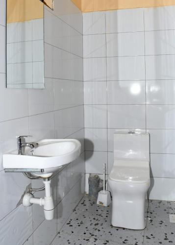 a white bathroom with a sink and a toilet at Airport Bliss House in Kisumu