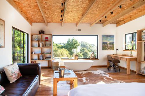 a living room with a large window and a tub at Granite Forest Chalet in Cape Town